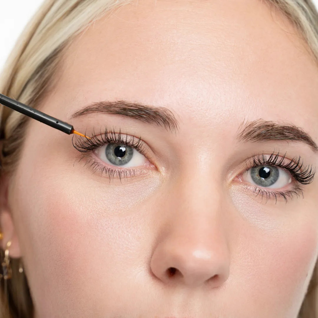 close up of woman applying lash serum