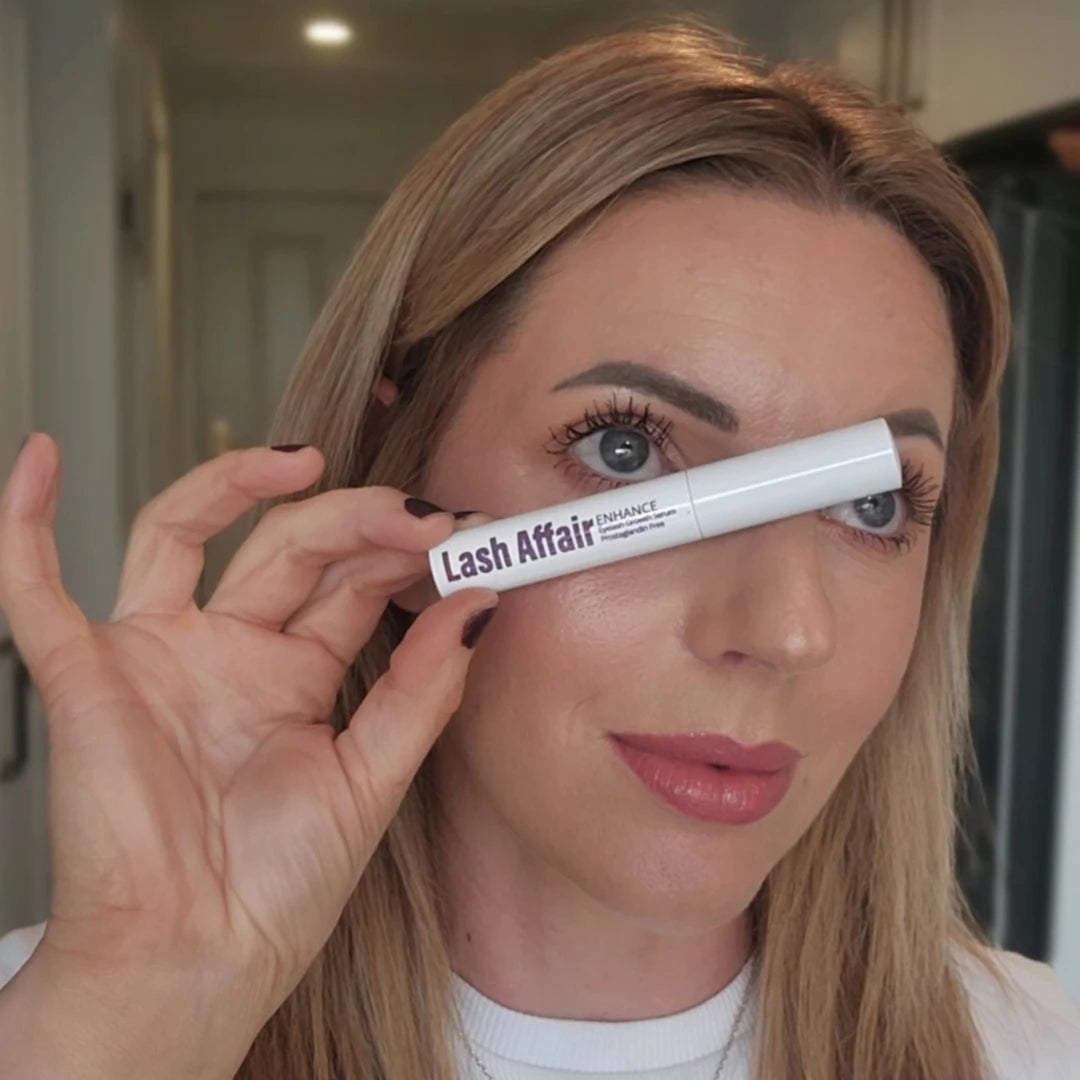 woman holding lash serum in front of eye